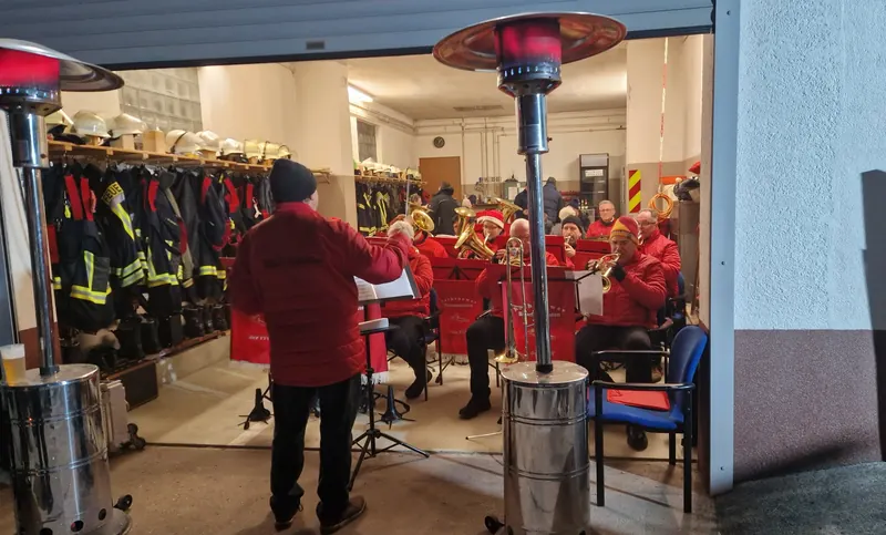 Blasmusik im geöffneten Gerätehaus der Feuerwehr Großwudicke zwischen Einsatzkleidung und Helmen