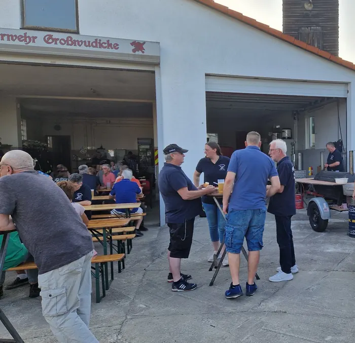 Sommerabend am Gerätehaus der Feuerwehr Großwudicke: Gäste an Biertischen, Kameraden am Grill